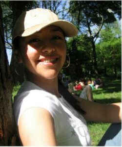 Maritza sonriente sentada junto a un árbol en Central Park, un día soleado.